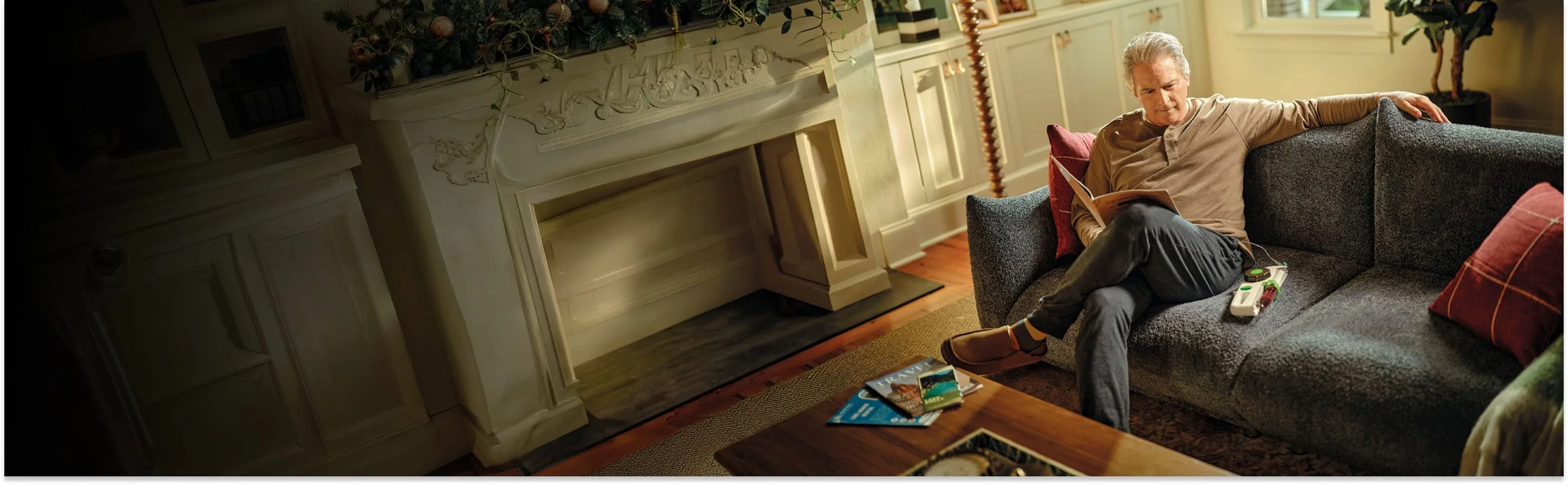 Older man reading on a couch with Hizentra infusion supplies nearby, actor portrayal