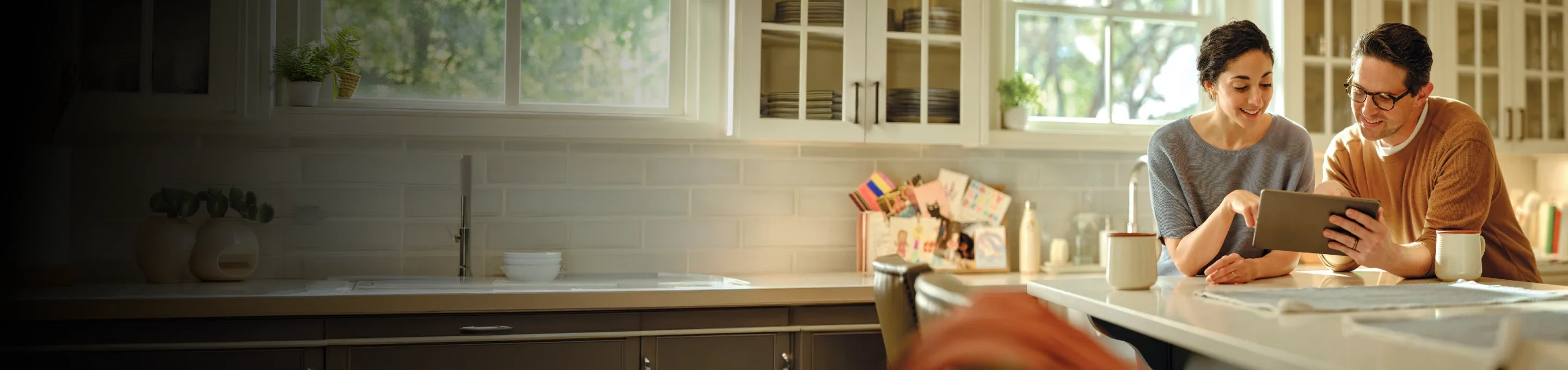 Couple sitting at a kitchen table looking at a tablet together