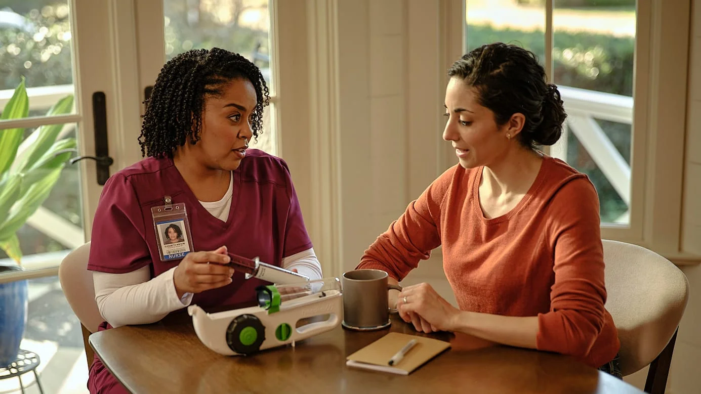 Nurse demonstrating a Hizentra infusion device during in-home training, actor portrayal